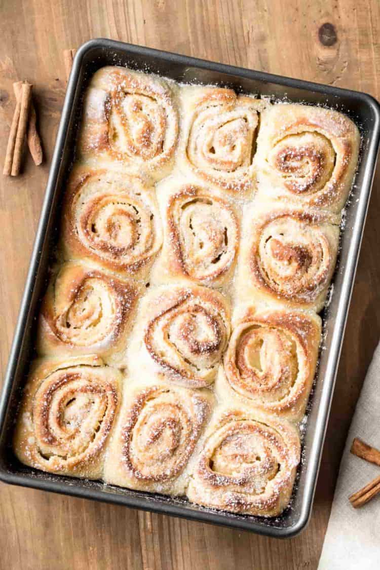 Cinnamon rolls in a baking sheet, dusted with powdered sugar.