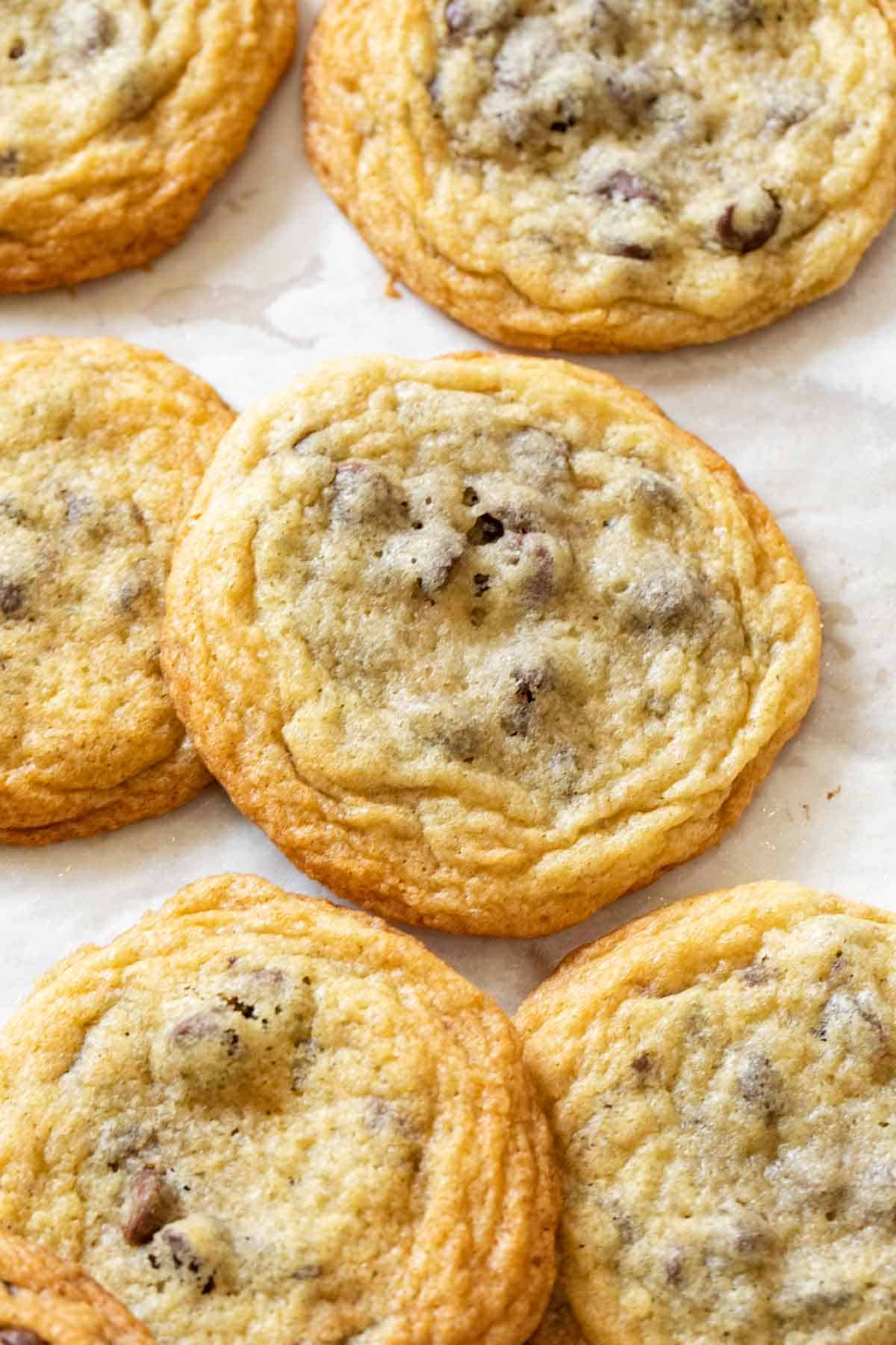 Chocolate chip cookies laid out on a baking sheet with parchment paper. 