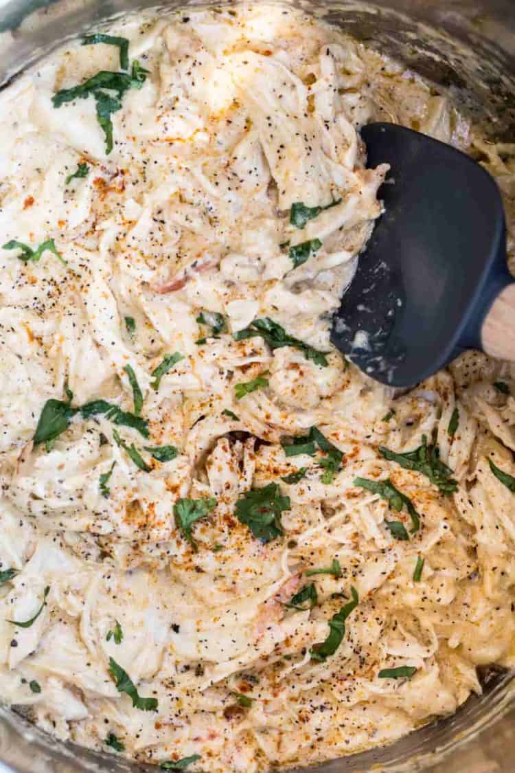 Instant Pot Crack Chicken Recipe topped with fresh greens and a spatula.