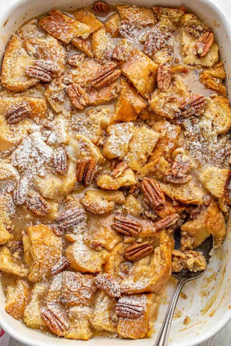 A white baking dish with maple pecan French toast casserole with a spoon. 