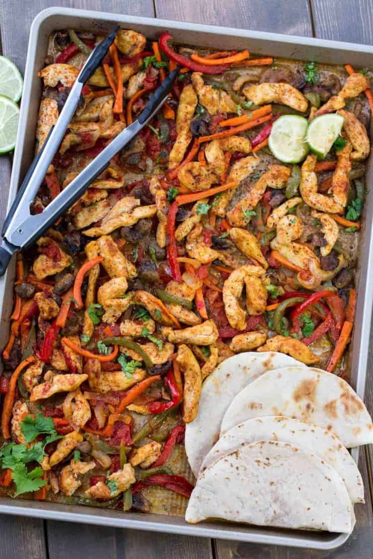 Chicken fajitas on a baking dish seasoning and baked with peppers, and onions.
