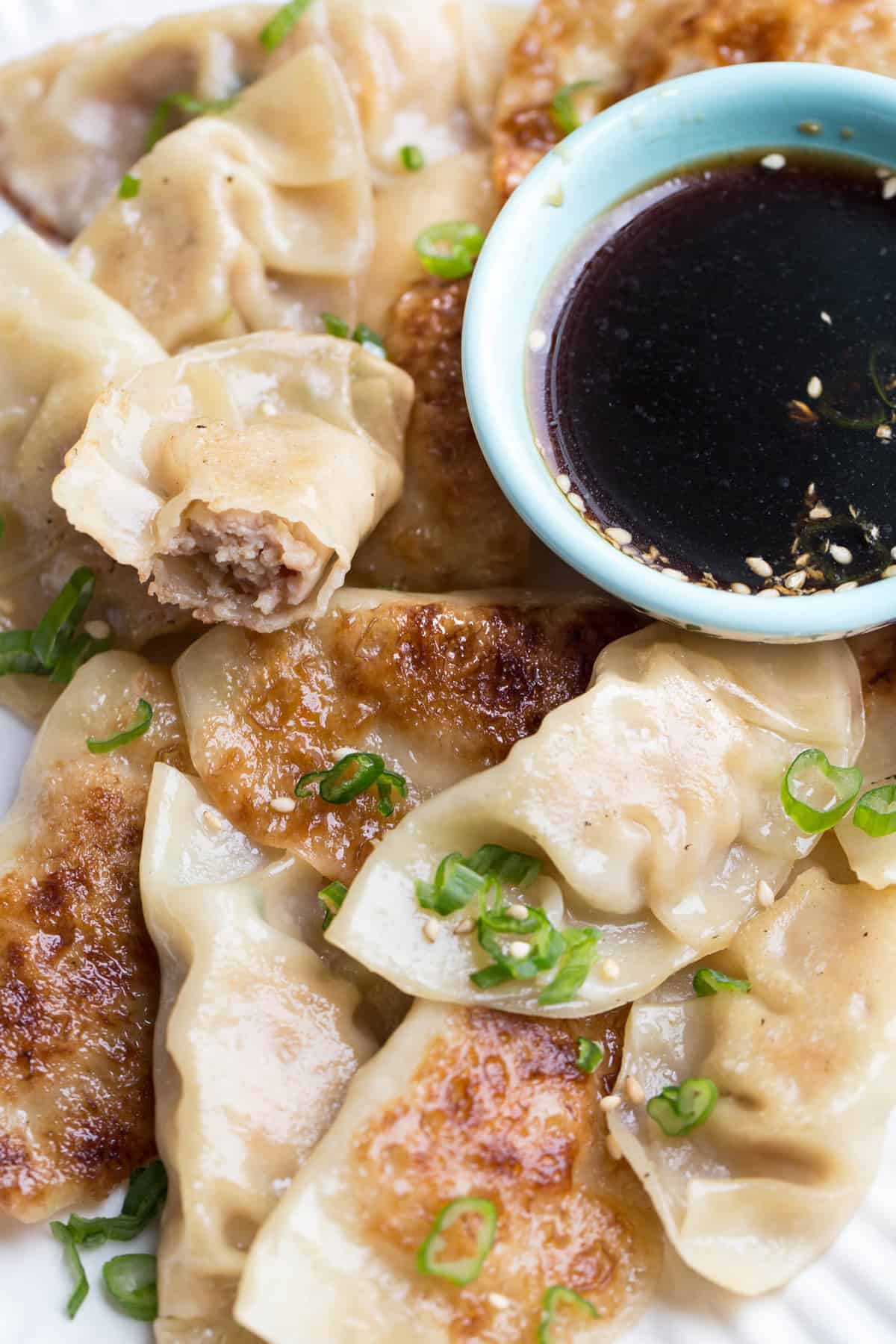 Chicken gyozas on a plate with a side dish of gyoza sauce.