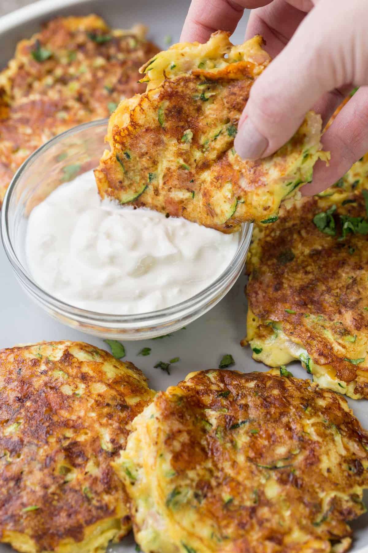 Zucchini Fritter dipped into the mayo mixture on a plate. 