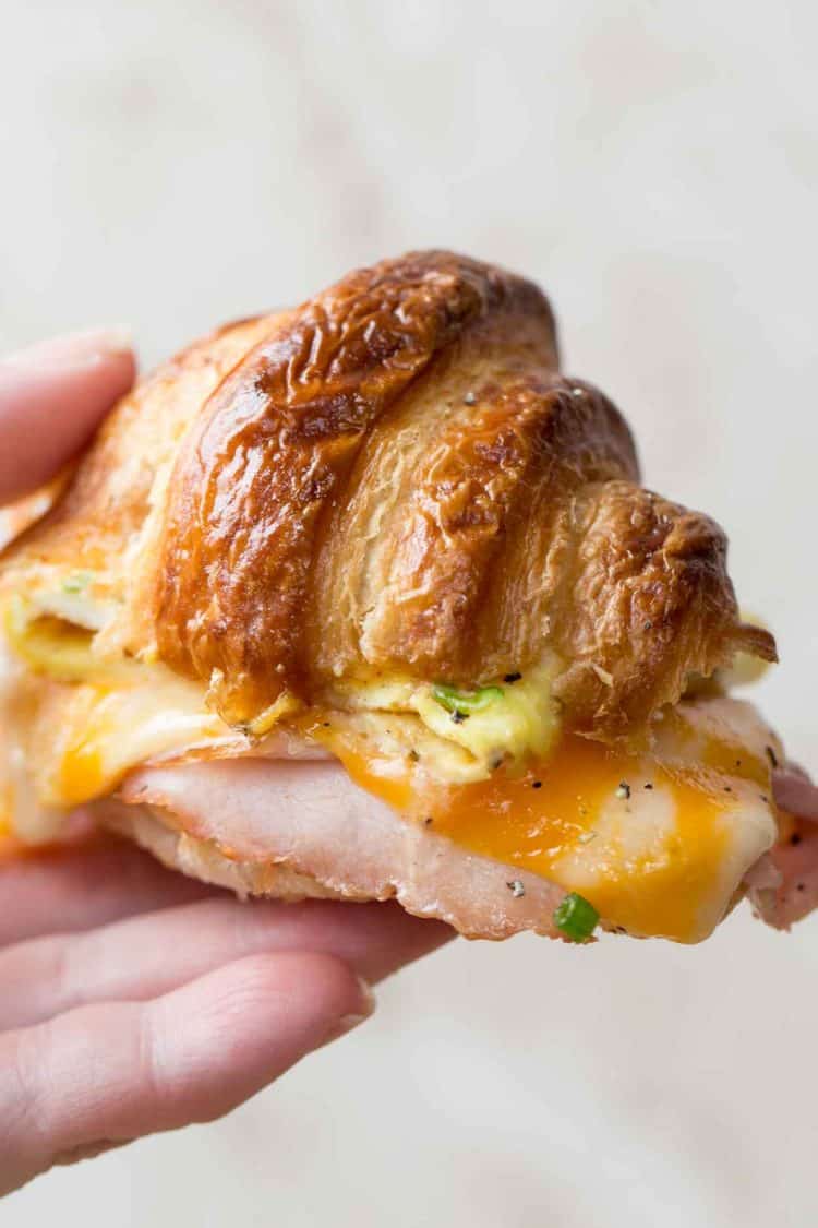 Croissant breakfast sandwich being held.
