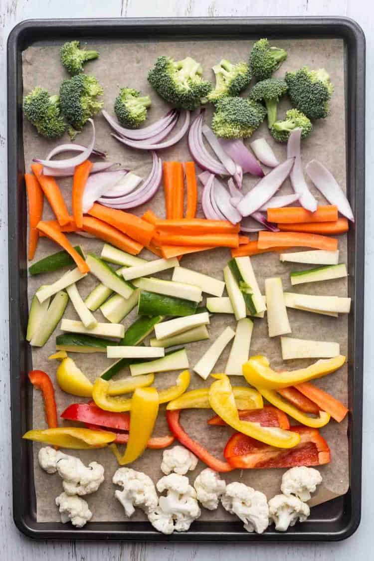 Roasted vegetables in a baking sheet mixed in a soy sauce mixture.