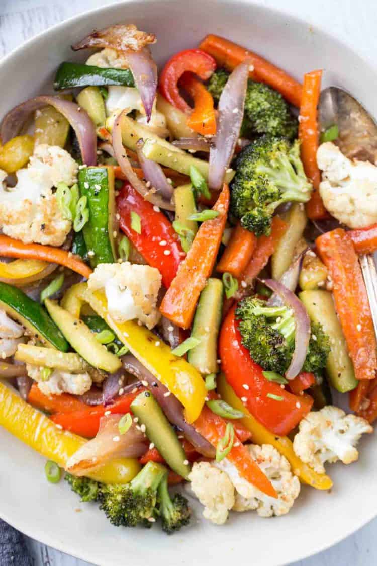 Roasted vegetables in a bowl topped with sesame seeds.