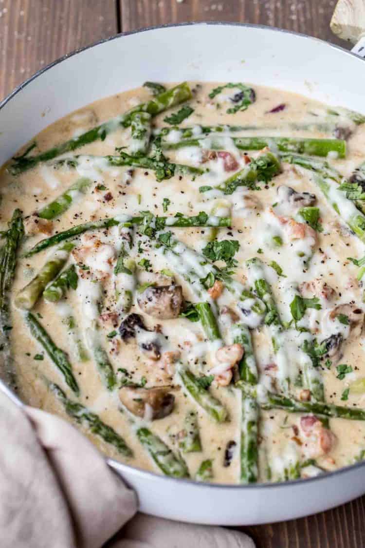 Creamy asparagus with mushroom sauce and bacon pieces topped with cheese and grated pepper.