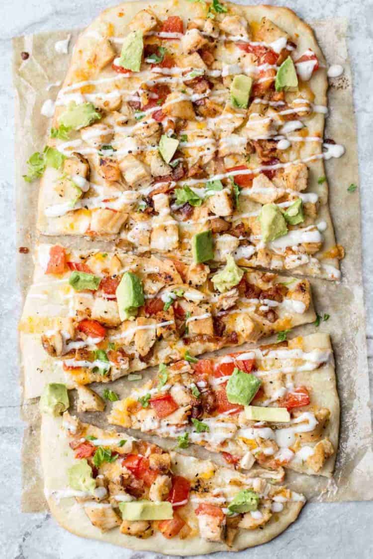 Simple flatbread recipe with a homemade crust, topped with chicken, avocado, bacon and ranch drizzle.