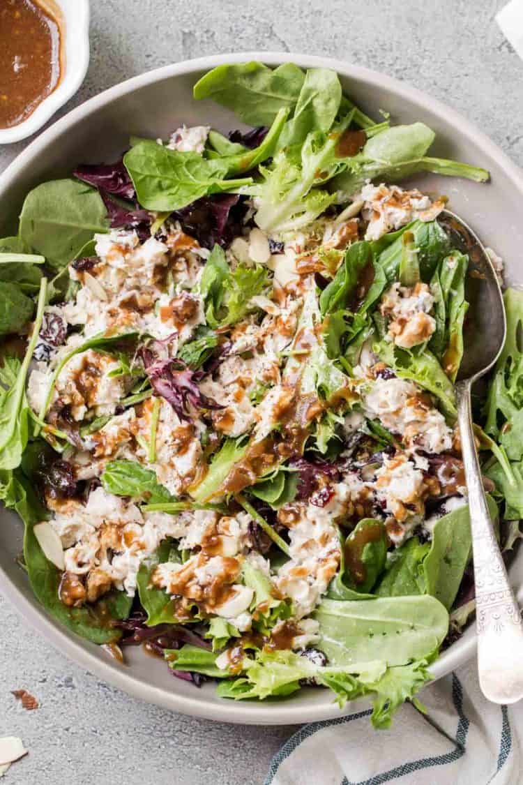 Chicken Salad recipe in a bowl topped drizzled baslamic vinaigrette dressing next to a spoon.