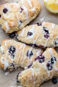 Four blueberry scones, laid out next to each other, drizzled with glaze.