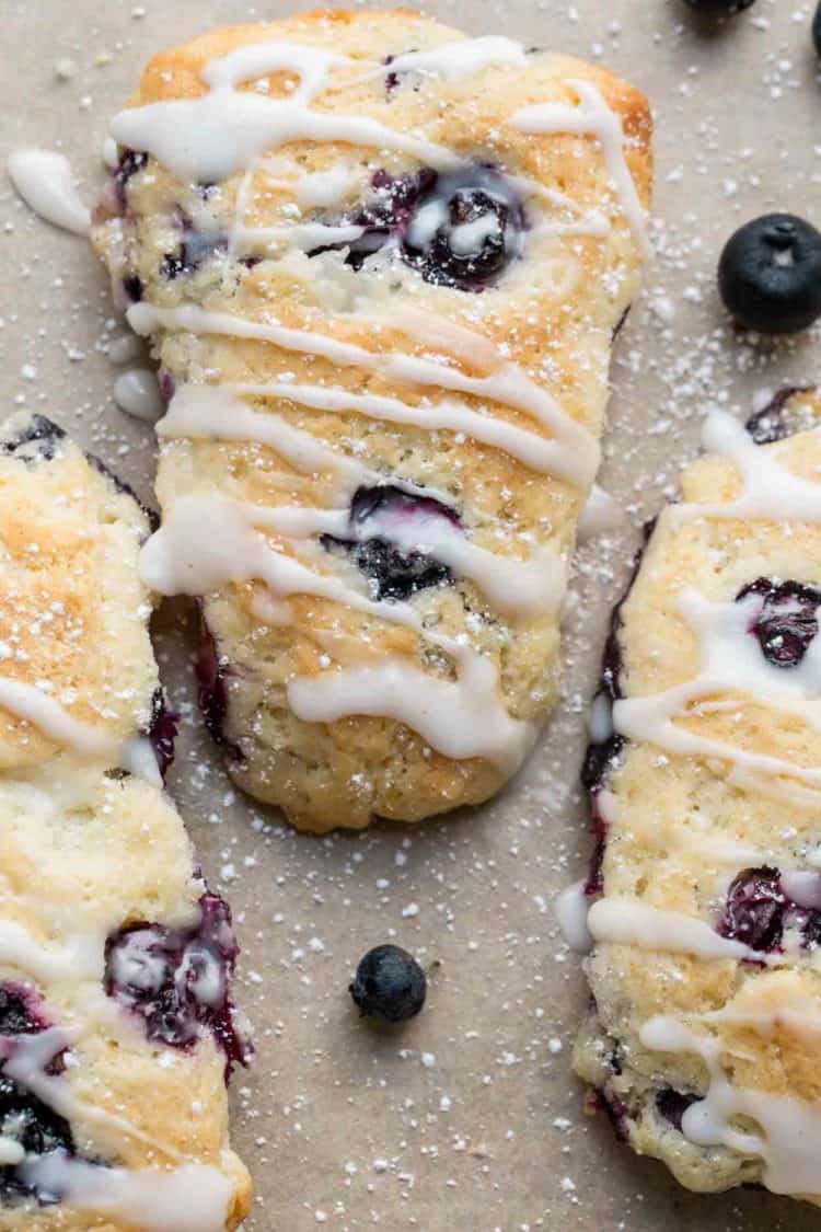 Close up of a scone with fresh blueberries and lemon.