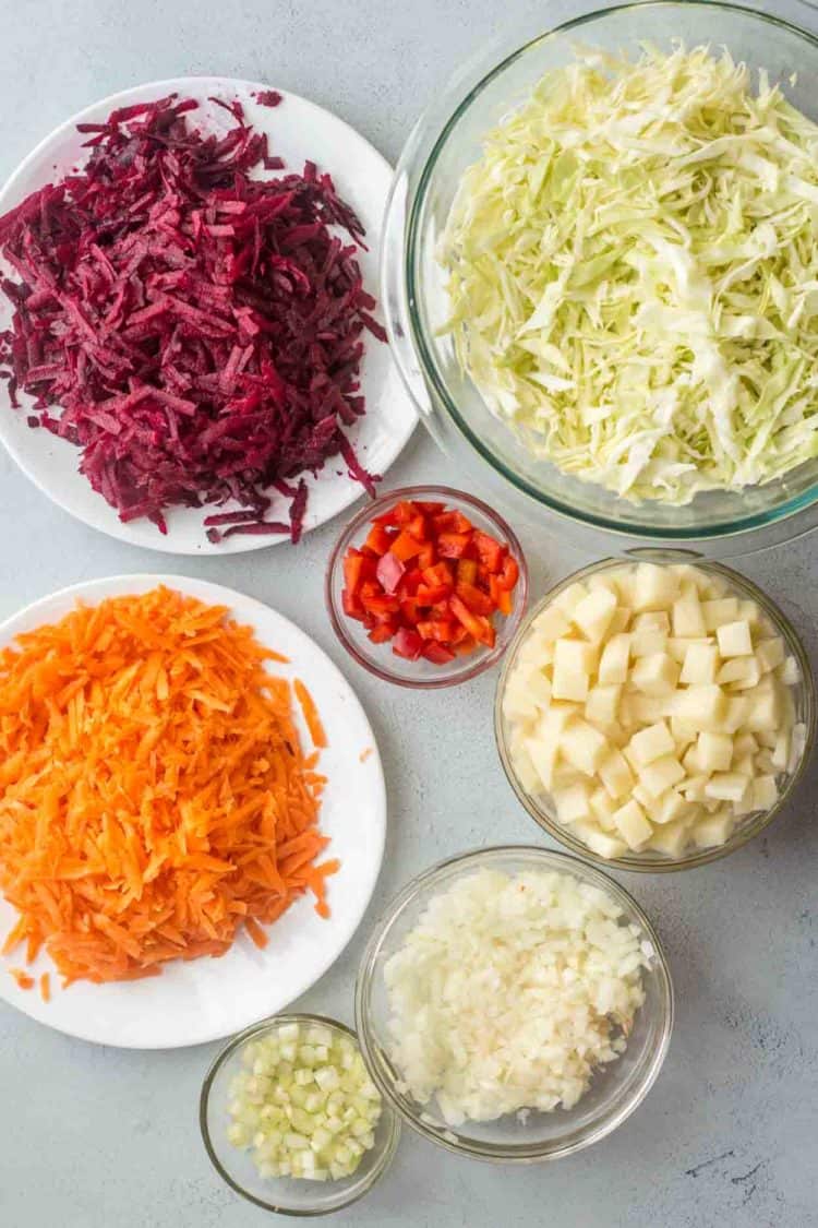 All of the vegetables shredded and cubed in bowls on a platter. 