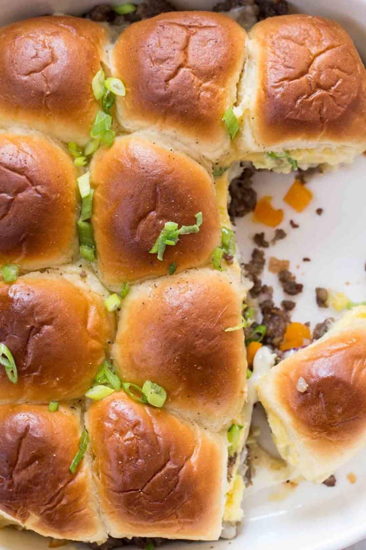 Sausage egg breakfast sliders in a casserole dish topped with fresh greens.