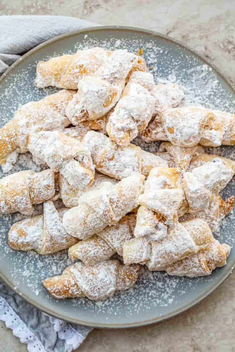A plate of Rugelach cookies topped with powdered sugar. 