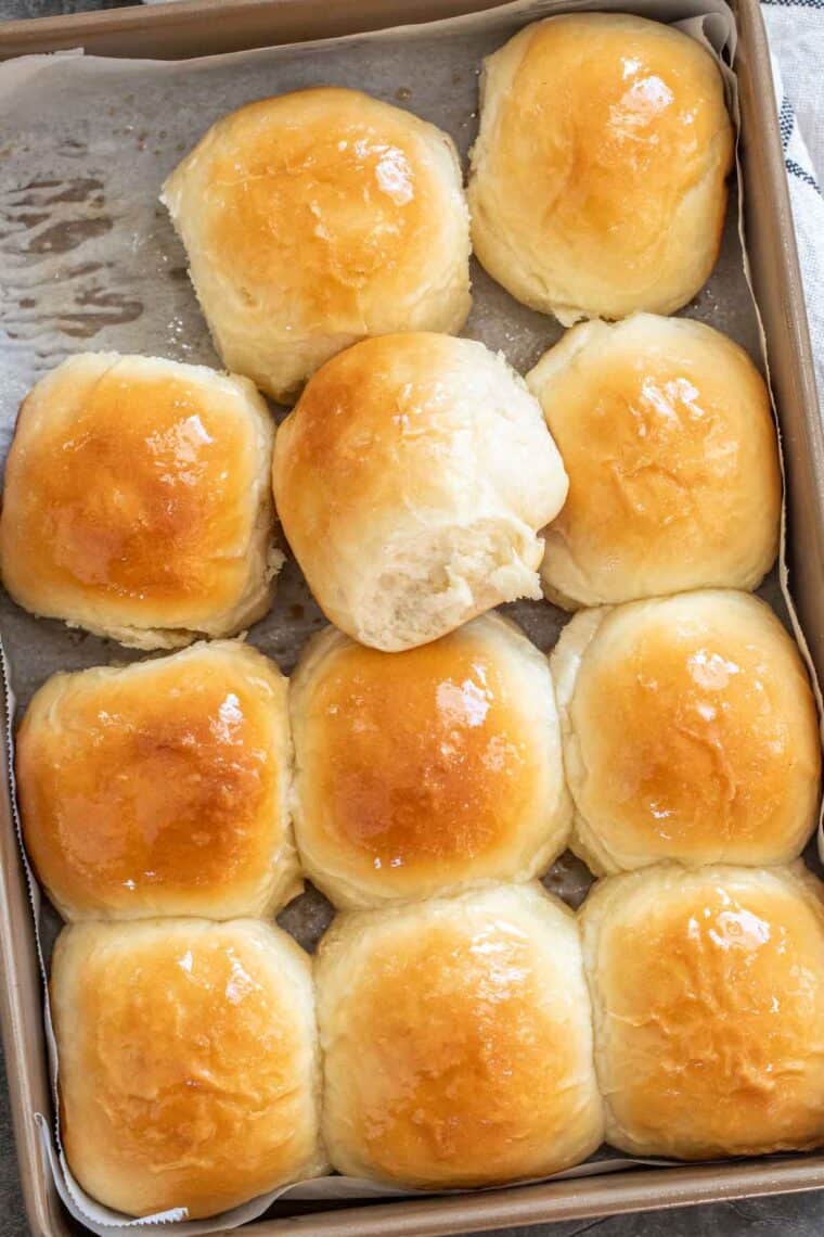 Dinner rolls rolled with butter in a baking dish.