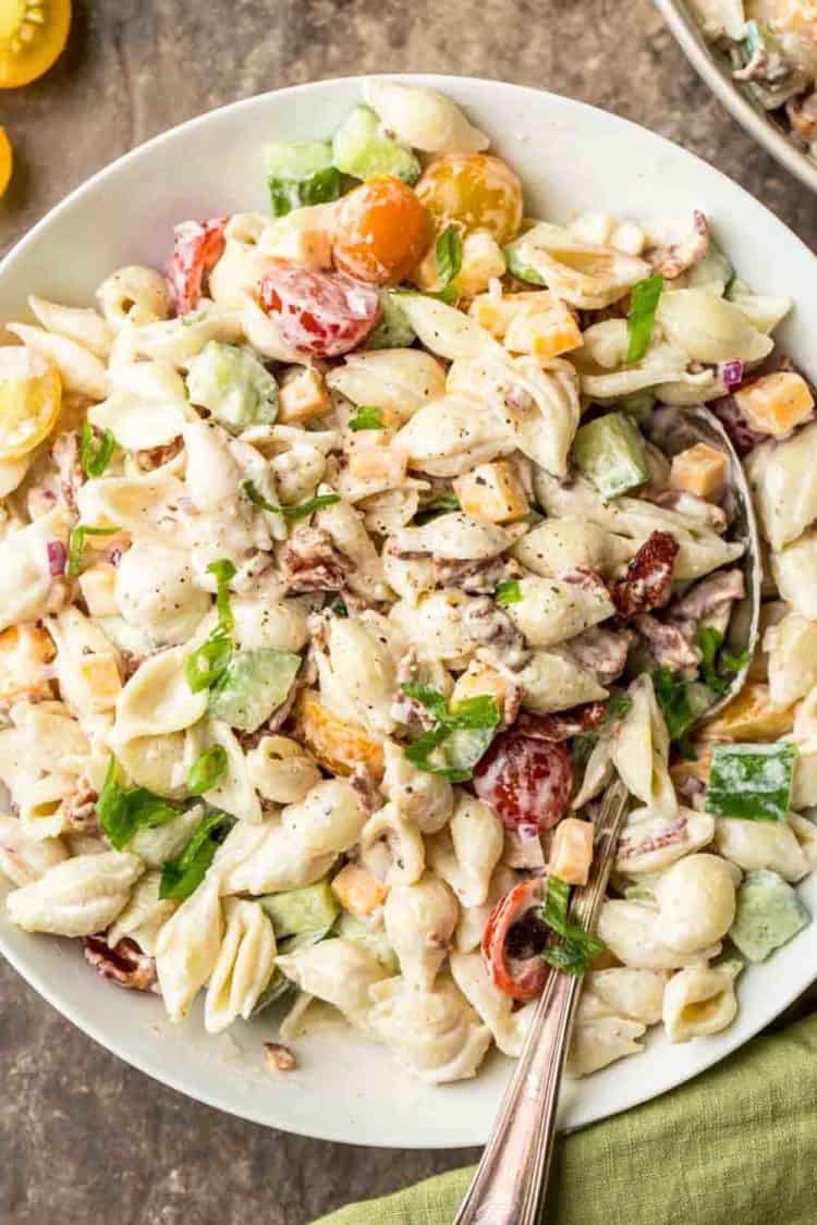 Easy pasta salad recipe in a bowl with cheese, bacon, cucumbers and a creamy dressing.