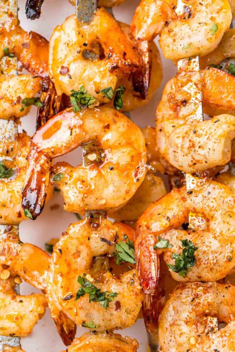 Grilled shrimp on skewers topped with fresh greens and a spicy marinade. 
