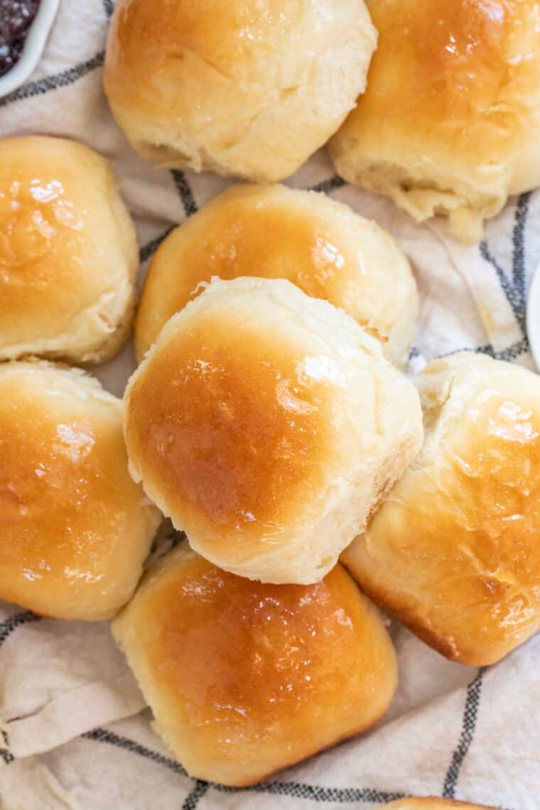 Dinner rolls laid out on a towel topped with butter. 