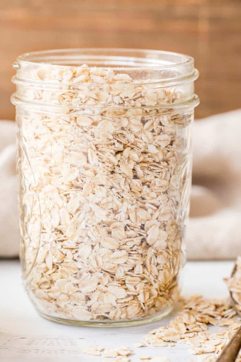 Dry oats in a mason jar next to a spoon of oatmeal. 