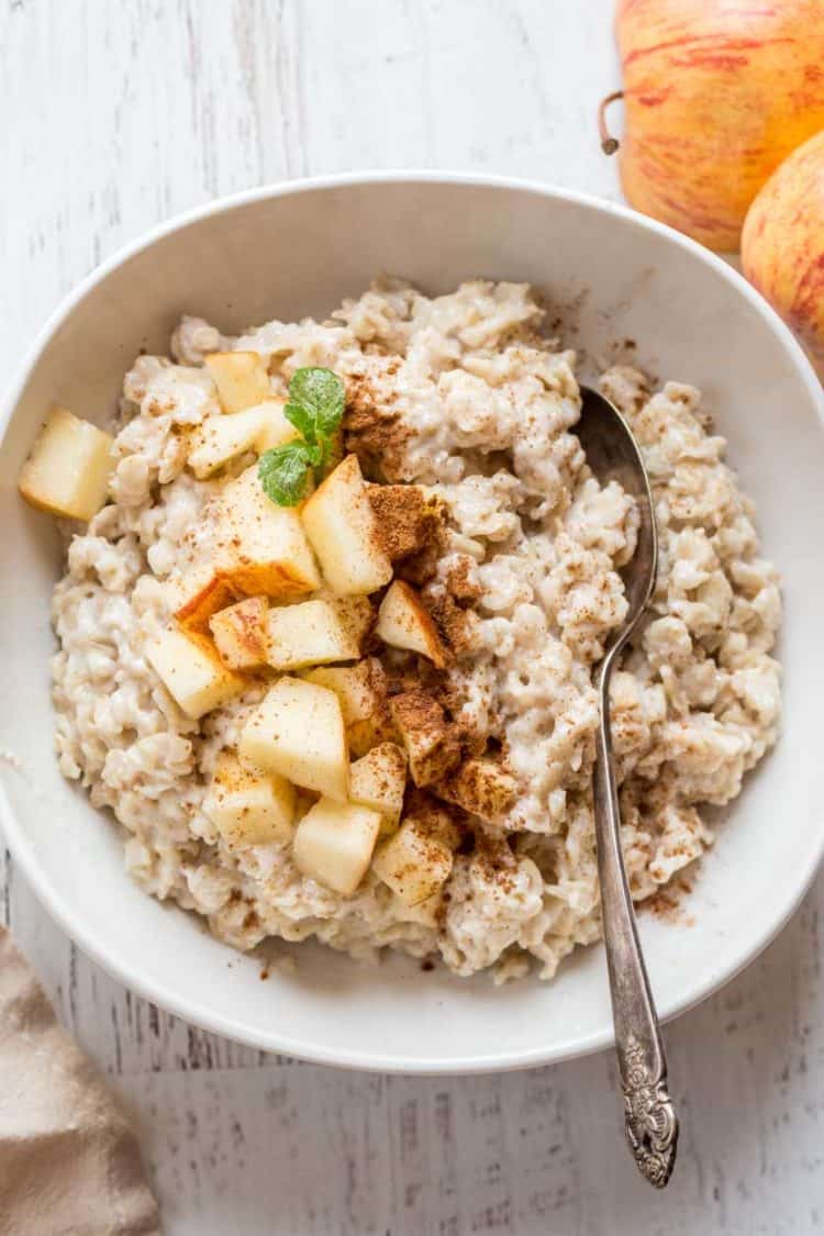Oatmeal recipe topped with apples and cinnamon and a spoon. 