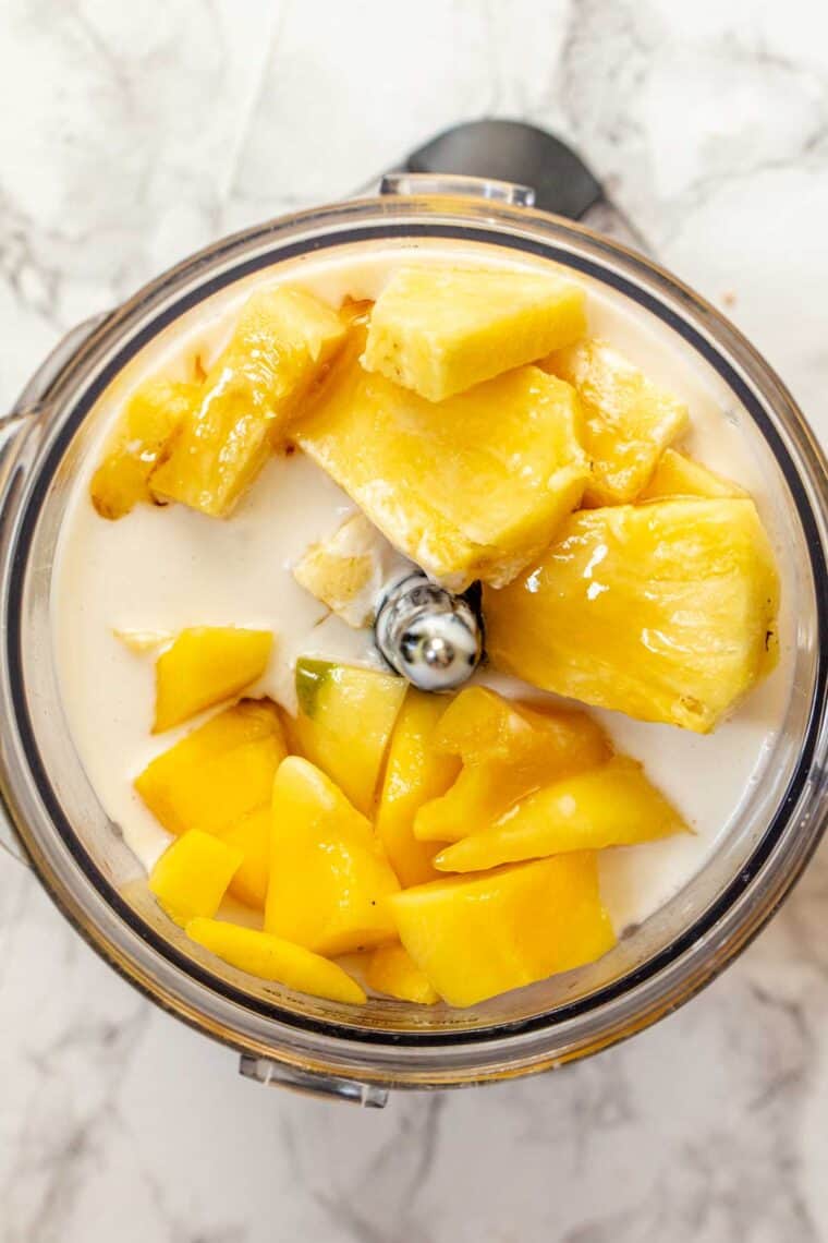 All of the ingredients for a mango smoothie in a blender. 