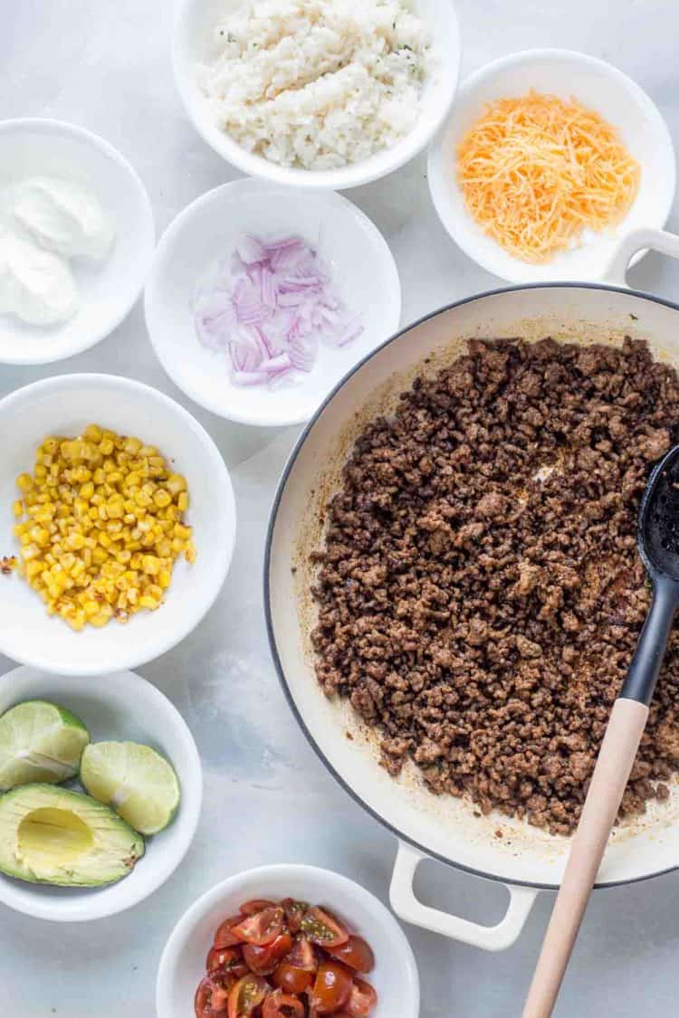 How to prepare a taco bowls with ground beef, corn, avocado, tomatoes, cheese and rice.