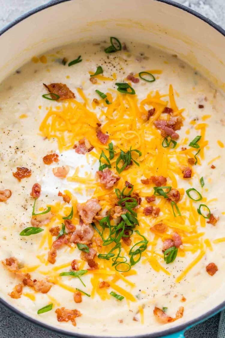 Easy potato soup in a dutch oven topped with bacon and cheese. 