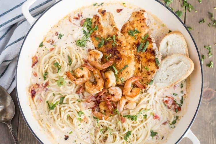 One pan chicken carbonara pasta in a skillet with bread slices and fresh greens.