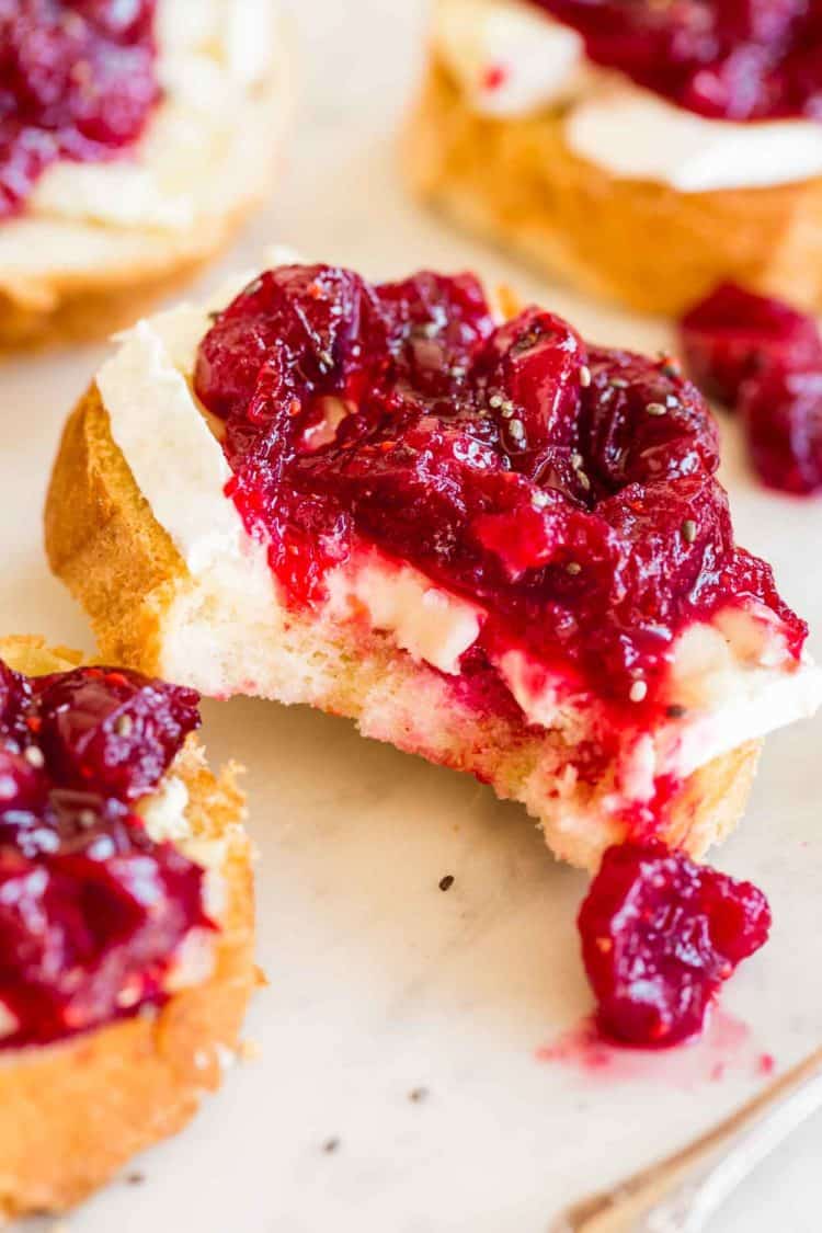 A slice of crostini with brie cheese and a sweet and sour cranberry sauce.