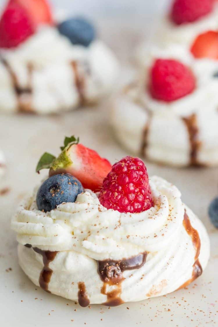Mini boccone dolce on a plate topped with whipped cream and fresh berries. 