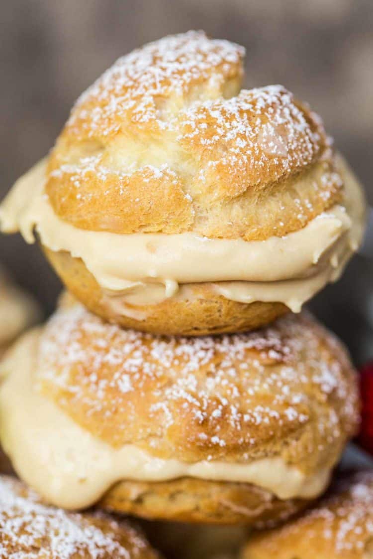 Two cream puffs filled with dulce de leche filling dusted with powdered sugar.