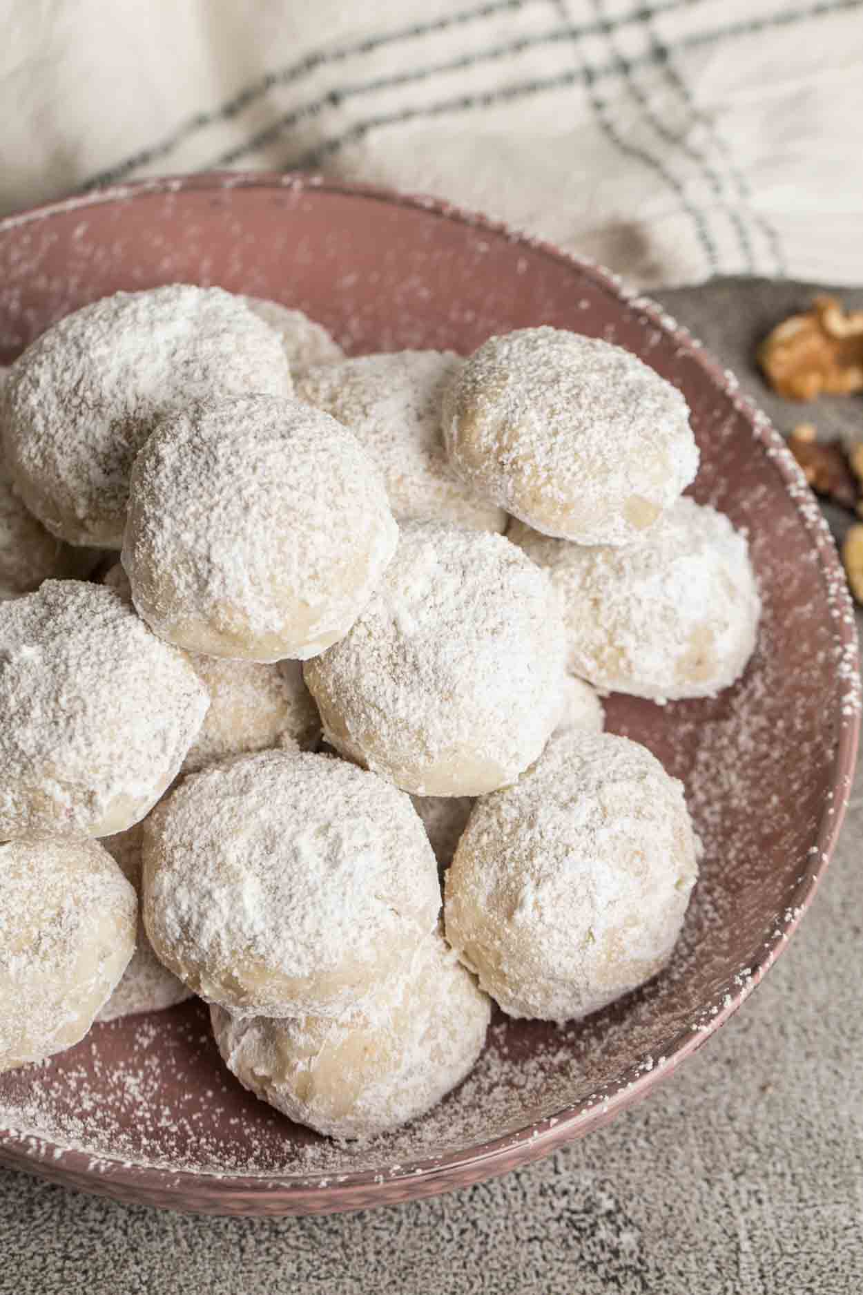 Snowball cookies coated in powdered sugar in a bowl.