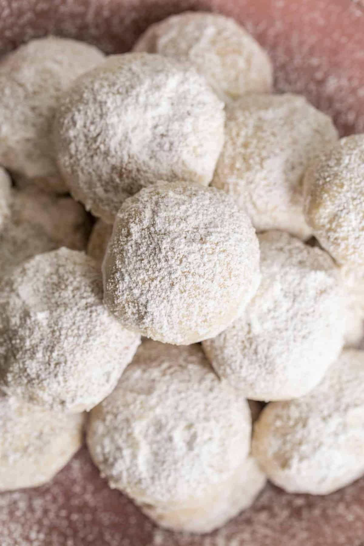 Soft and chewy snow ball cookies on a bowl with powdered sugar.