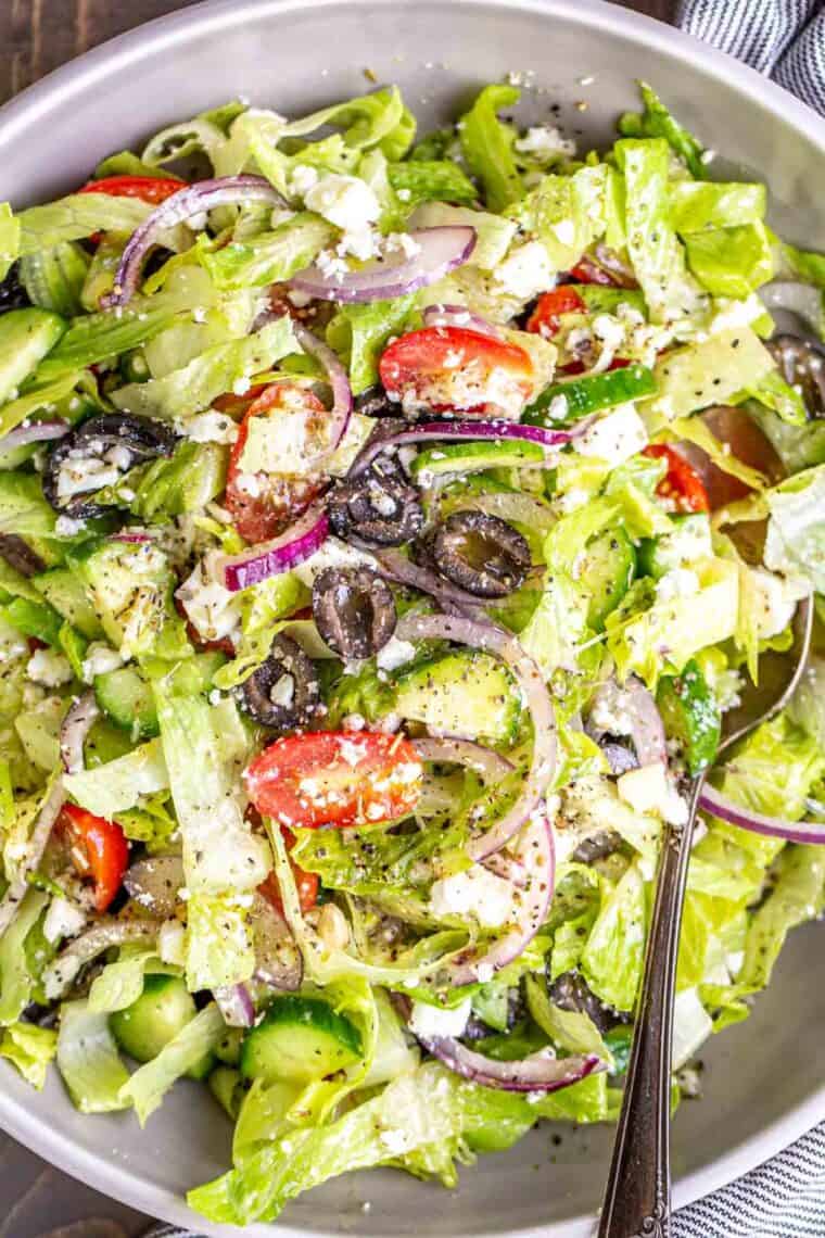 A bowl of Greek salad tossed with homemade salad dressing. 