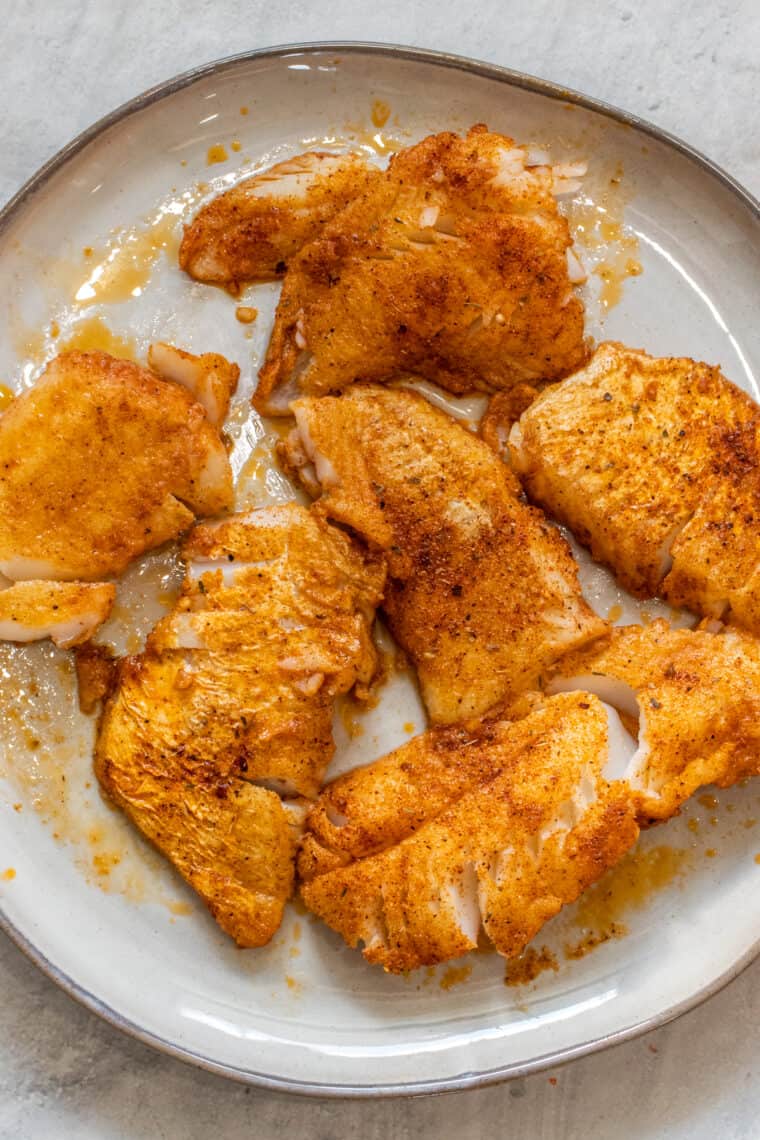 Seasoned and cooked fish fillets on a plate ready to be used for fish tacos. 