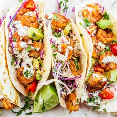 Four shrimp tacos topped with slaw.