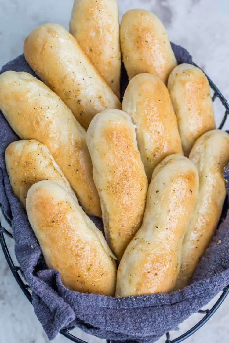 Garlic breadsticks in a bread basket topped with a garlic butter spread.