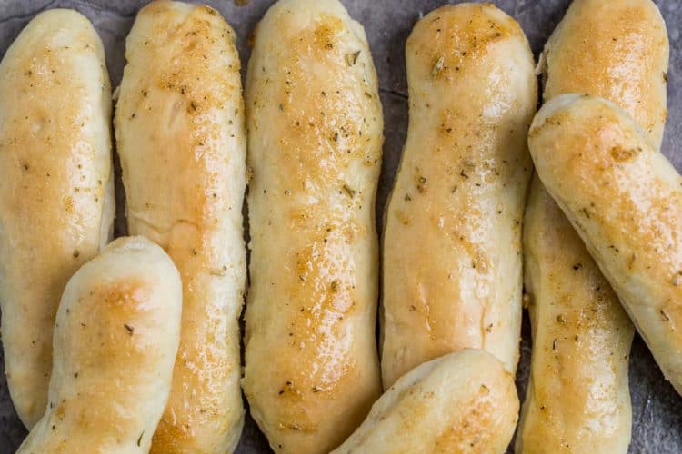 Olive garden breadsticks next to each other topped with a garlic butter spread.