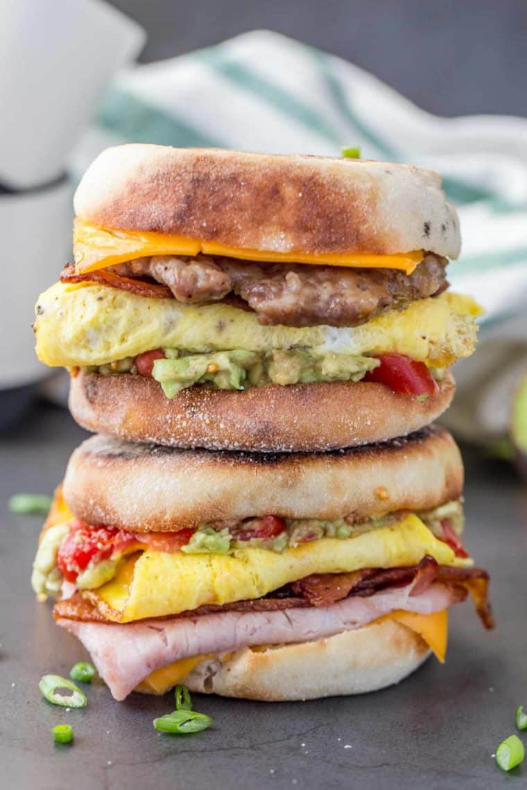 Two breakfast sandwiches stacked on top of each other topped with fresh greens.