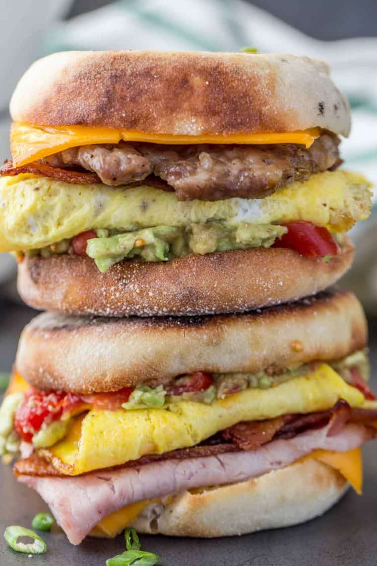 Breakfast sandwich on top of each other loaded with cheese, meat, eggs and toppings. 