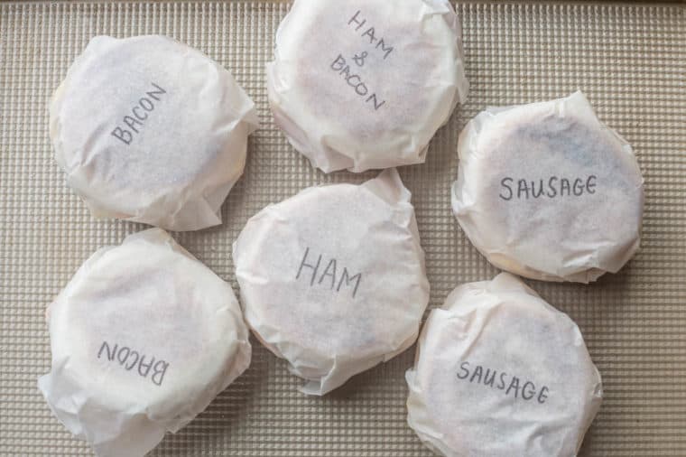 Breakfast sandwiches wrapped in parchment paper and labeled. 