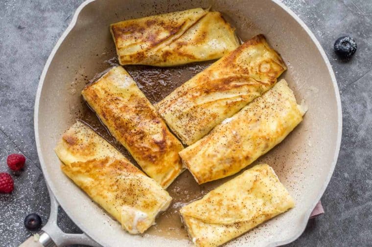 Sweet crepes sauteed in a skillet topped with powdered sugar. 