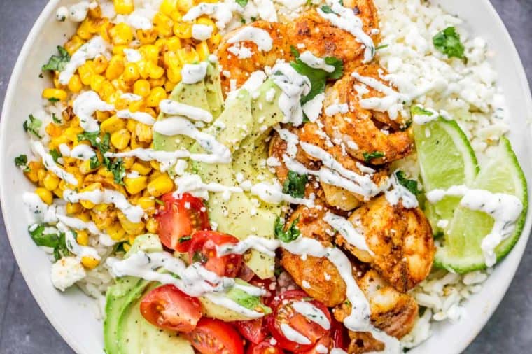 Shrimp rice bowl topped with cilantro lime dressing and fresh greens.
