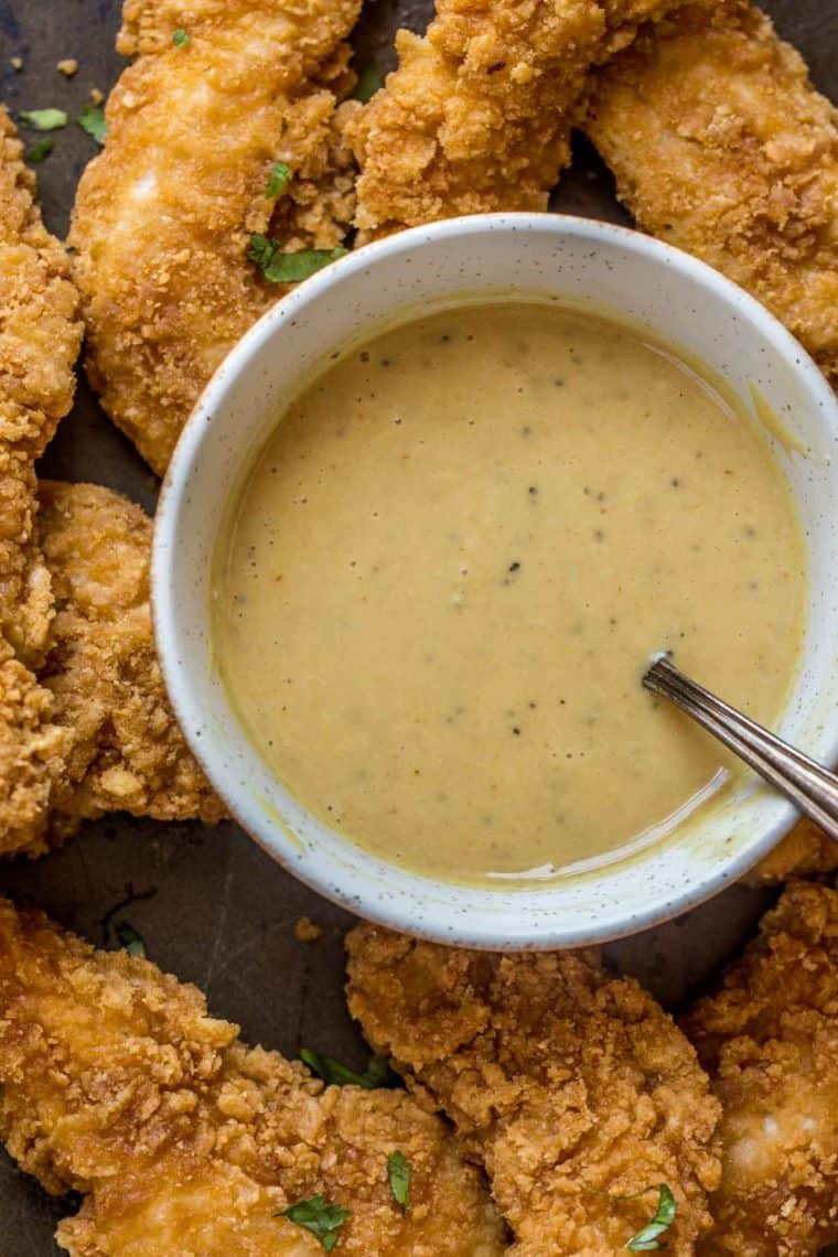Chick fil a sauce in a white bowl next to crispy chicken tenders.