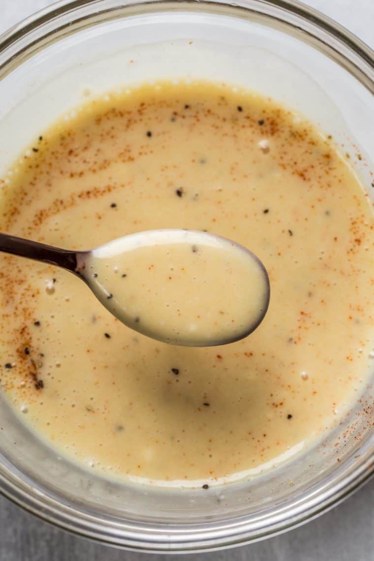 Homemade honey mustard sauce in a glass bowl with a spoon.