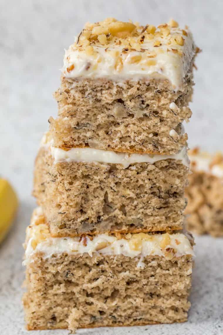 Three slices of banana cake stacked on top of each other loaded with chopped walnuts.