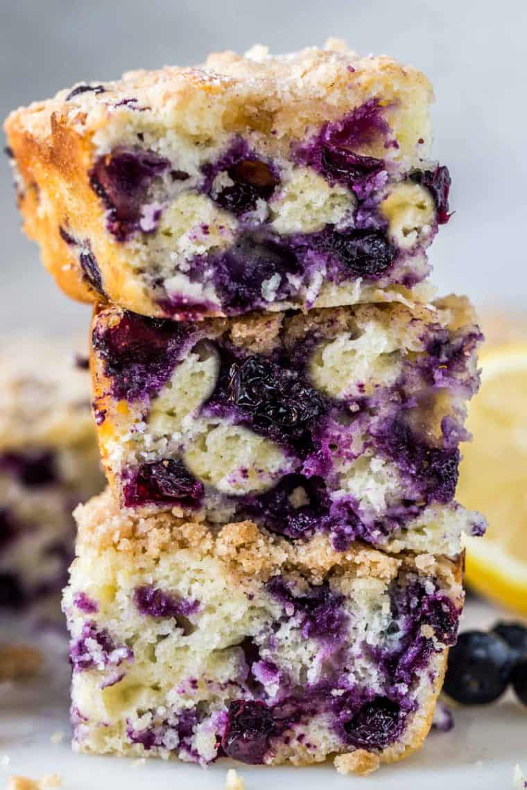 Blueberry coffee cake slices stacked on top of each other sprinkled with powdered sugar.