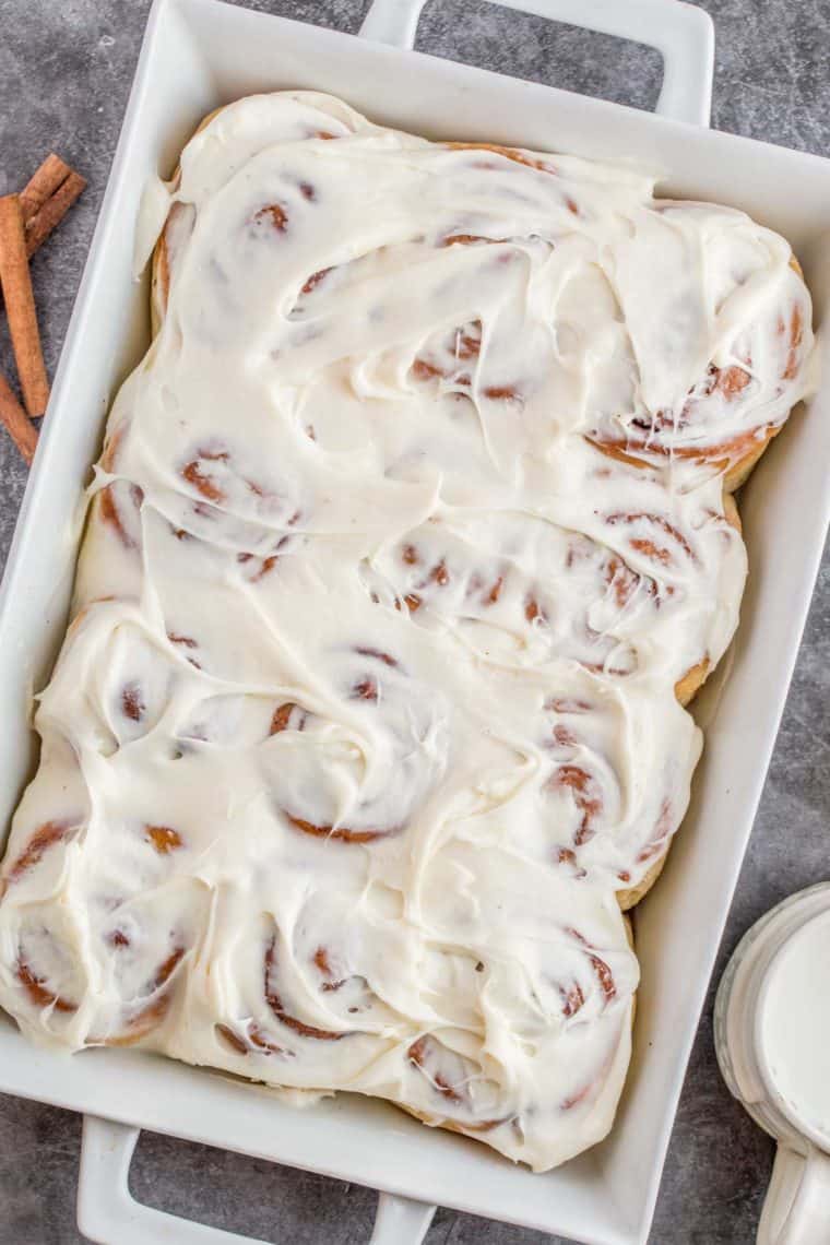 A casserole dish loaded with sweet cinnamon rolls topped with cream cheese frosting.