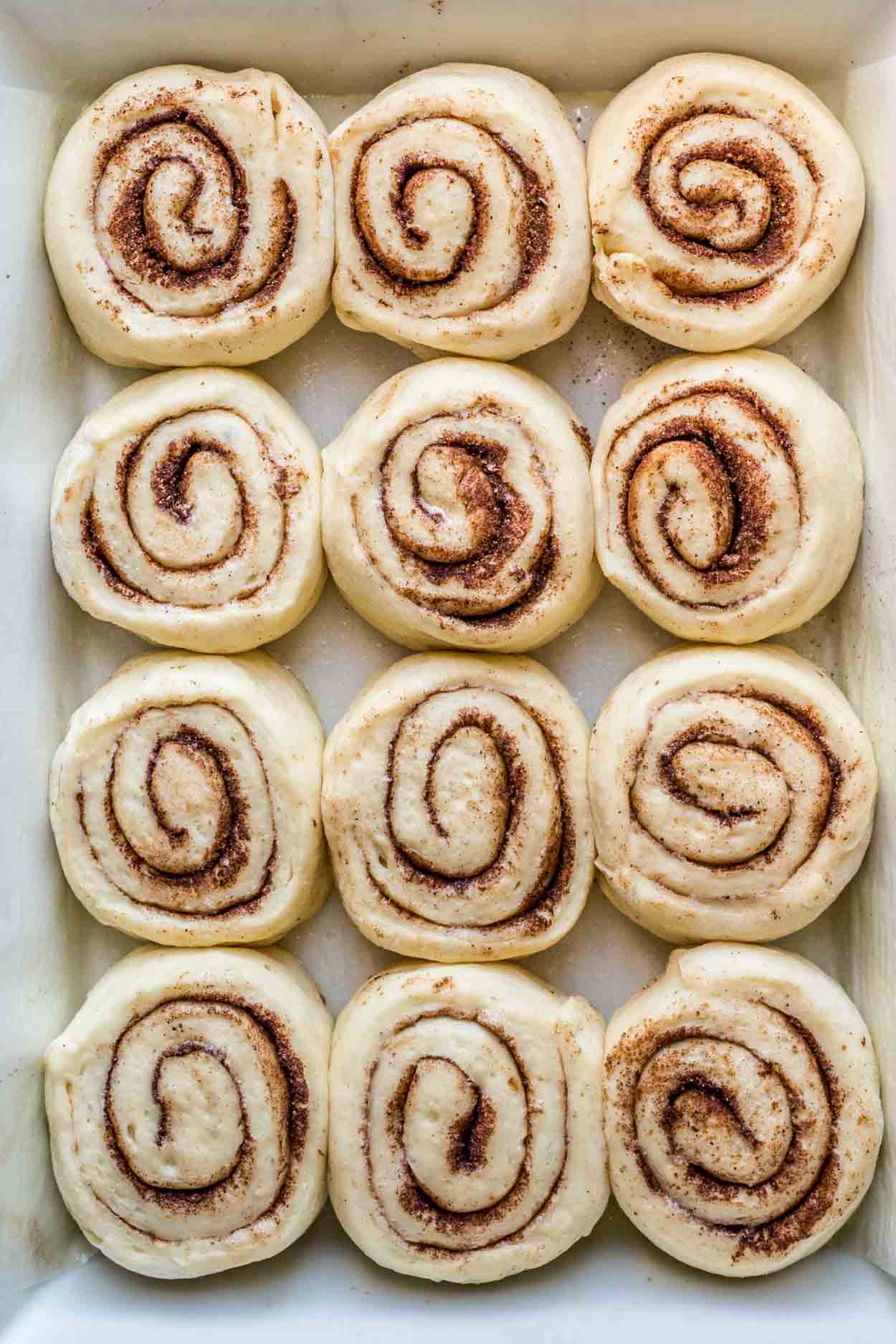 Cinnamon buns arranged in a baking dish to rise.