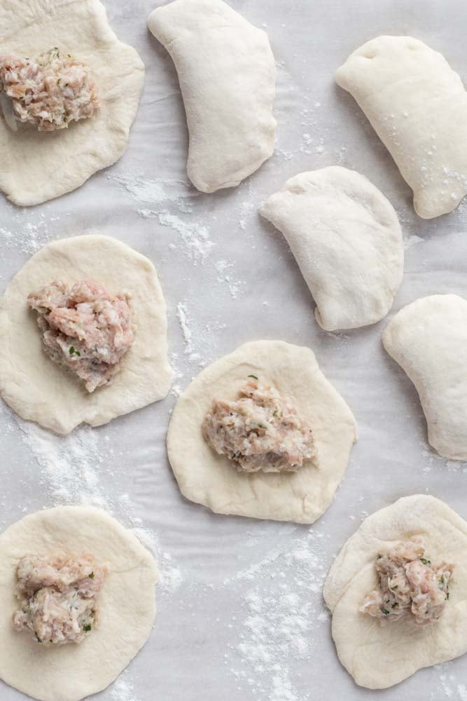 The flattened dough balls with the meat filling in the center.